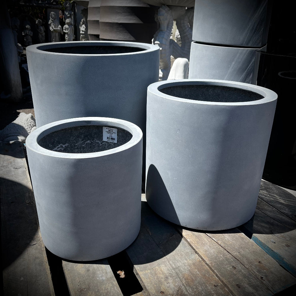 Set of gray lightweight concrete cylinder-shaped planters on a wooden surface