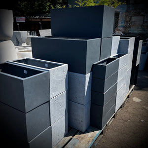 Stack of gray lightweightconcrete planters on a pallets outdoors.
